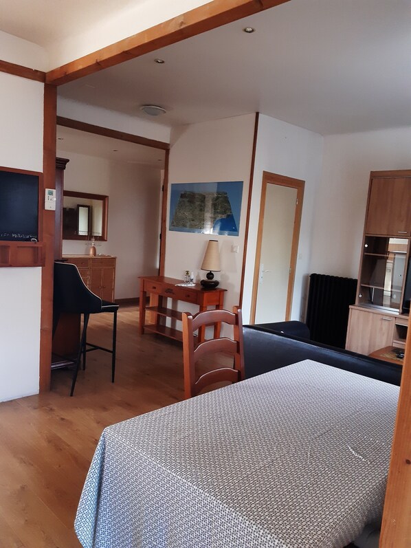 Une pièce comprenant un lit, un bureau, une chaise, un miroir et une carte accrochée au mur.
