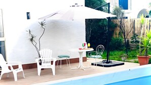 A swimming pool with white chairs and a table, surrounded by a white wall and a wooden fence. - Villa 'Nonna Anna' with Pool, Private Terrace, Wi-Fi, Wood Oven, and Barbecue (Siracusa)