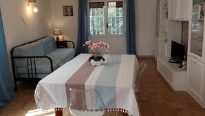 A room with a bed, a table with a vase of flowers, a lamp, a television, and a cabinet. - Villa 'Nonna Anna' with Pool, Private Terrace, Wi-Fi, Wood Oven, and Barbecue (Siracusa)