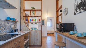 A kitchen with wooden cabinets, a microwave, and a bar area with stools. - Villa 'Nonna Anna' with Pool, Private Terrace, Wi-Fi, Wood Oven, and Barbecue (Siracusa)