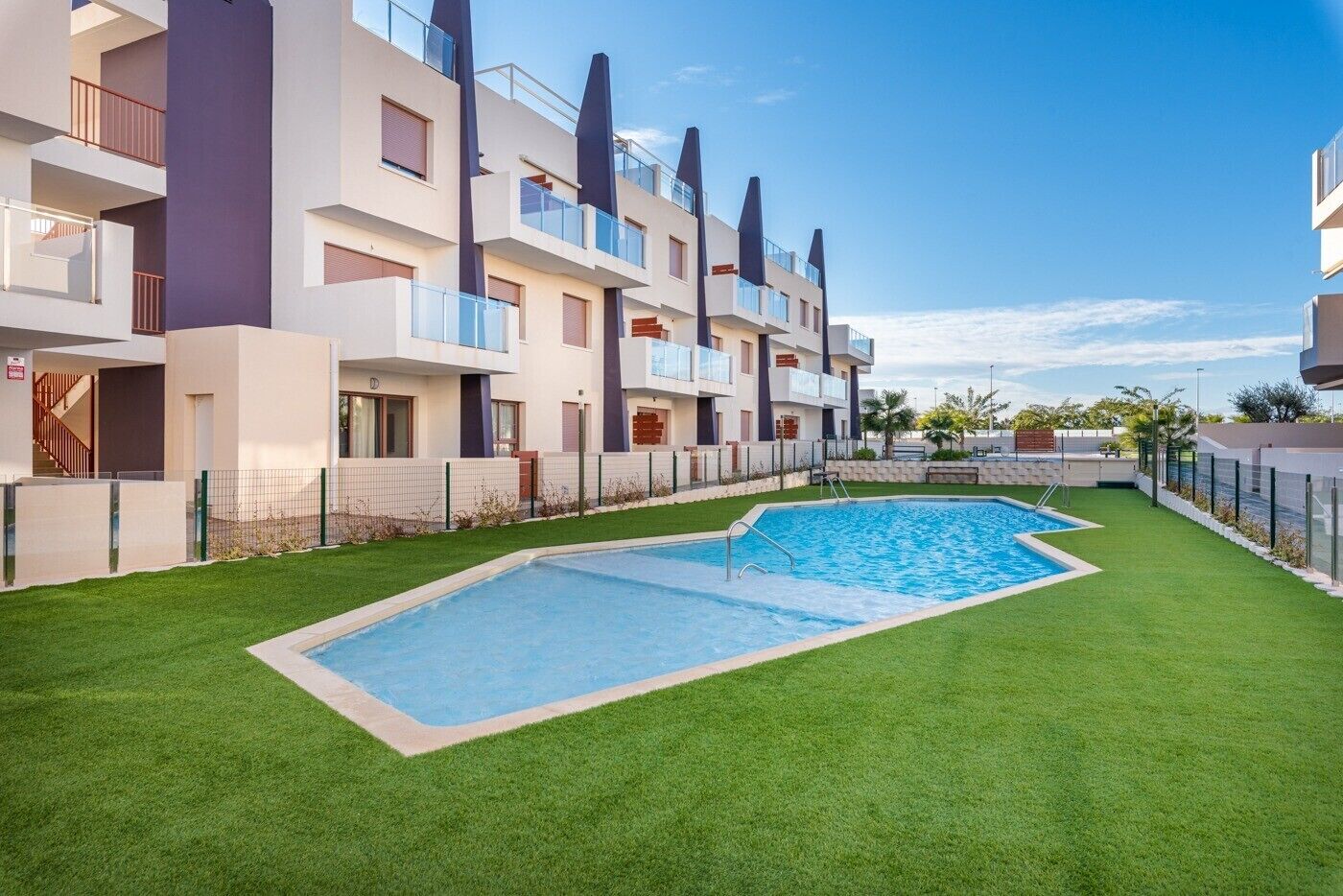 A modern apartment building with a swimming pool and green lawn.