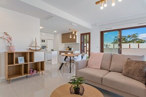 Een moderne woonkamer met een bank, een salontafel en een eetgedeelte met stoelen.