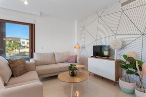 Een moderne woonkamer met een bank, salontafel, televisie en decoratieve planten.