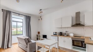 A modern kitchen with a dining area, a sofa, and a view of the outdoors. - Apartment 'Azores4fun' with Wi-Fi & AC (Horta)