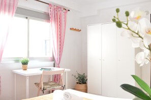 Quarto com cama, escrivaninha, cadeira, guarda-roupa e janela com cortinas.