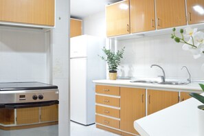Uma cozinha moderna com armários de madeira, fogão embutido, geladeira e pia.
