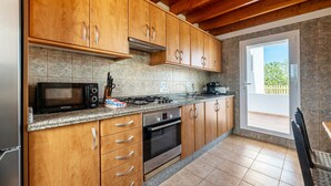 Une cuisine avec des meubles en bois, un four à micro-ondes, une cuisinière, un four et une vue sur l’extérieur.