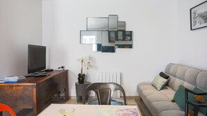 Un salon moderne comprenant un canapé, un téléviseur, un bureau et une œuvre d’art murale originale.