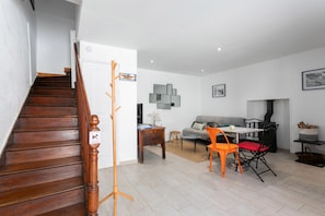 A staircase leading to a living area with a sofa, a dining table with chairs, and a fireplace.