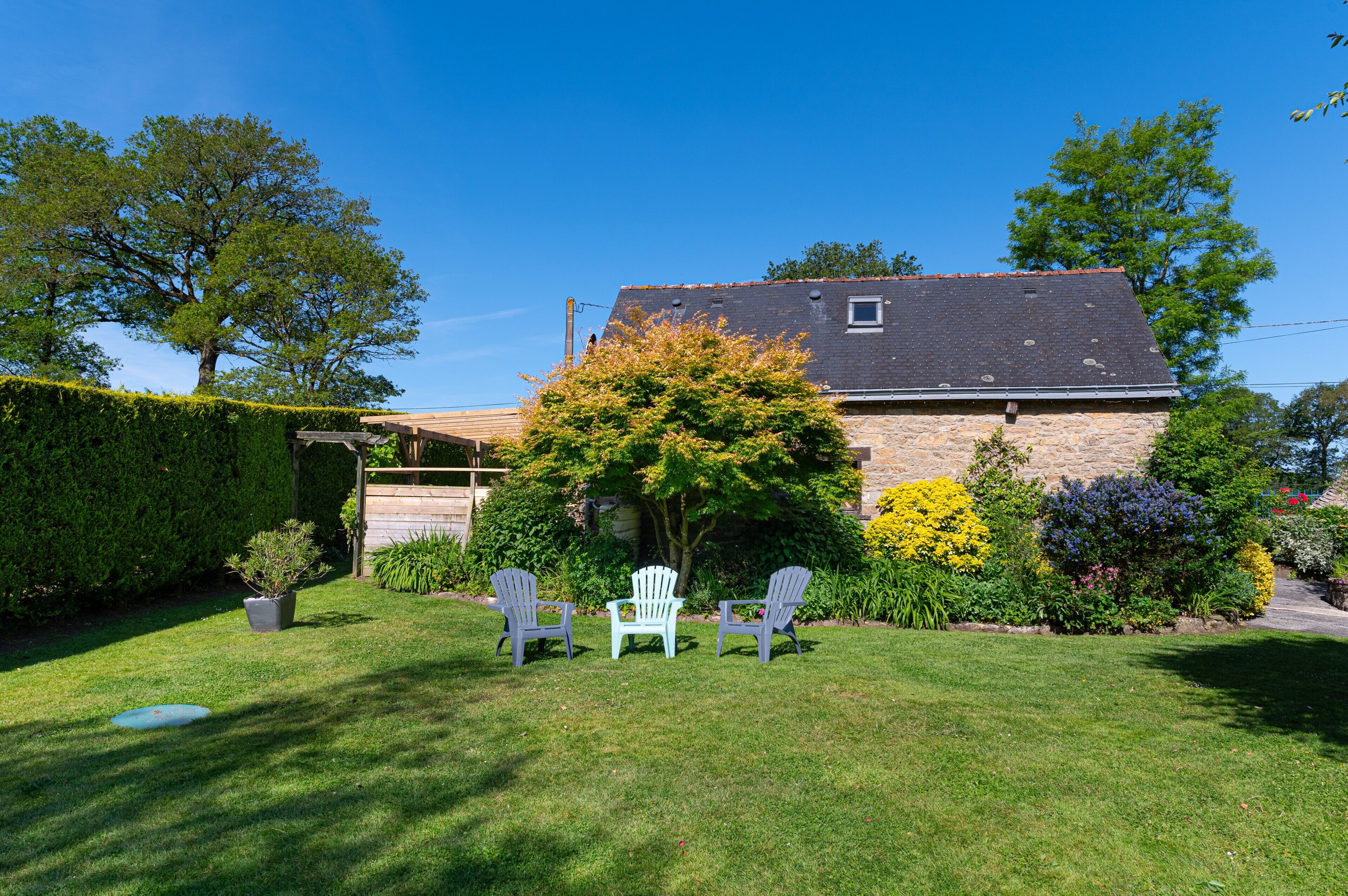 Une maison avec une façade en pierre, un toit en pente et une petite fenêtre.