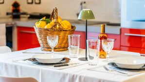 Una mesa de comedor con platos, cubiertos, vasos, una botella y una cesta de limones.