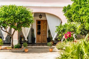 A building with a wooden door, potted plants, and a tiled entrance.