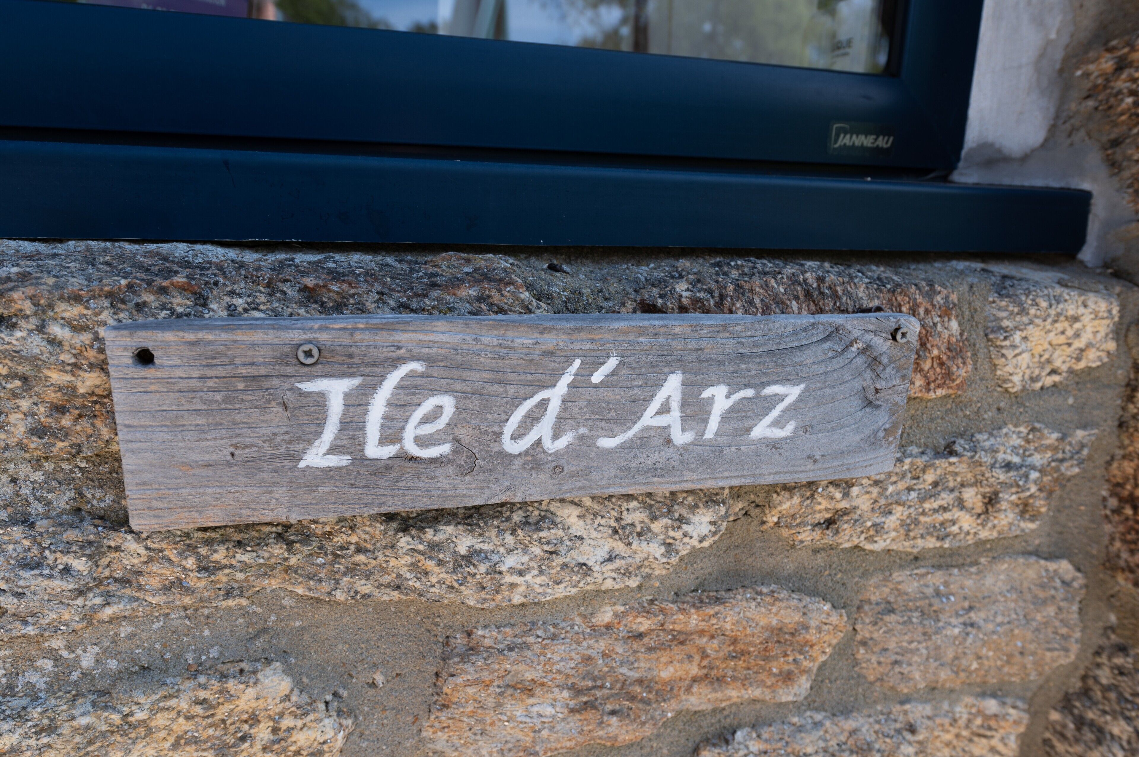 A wooden sign with the inscription 'Ile d'Az' mounted on a stone wall.
