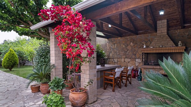 A stone patio with potted plants, a wooden table and chairs, and a stone fireplace. - Apartment 'Villa Rita' with Shared Garden, Wi-Fi and Air Conditioning (?e???da)