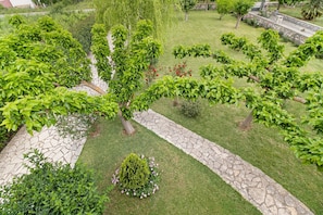 A landscaped garden with a stone pathway, neatly trimmed hedges, and various trees. - Apartment 'Villa Rita' with Shared Garden, Wi-Fi and Air Conditioning (?e???da)