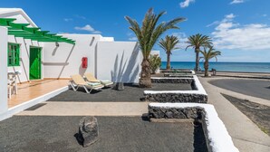 A white building with green accents, a stone pathway, and palm trees. -  'Alma Ocean View' with Sea View, Shared Pool and Wi-Fi (Puerto del Carmen)