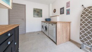 Ett tvättrum med tvättmaskin, torktumlare och en bänkskiva i trä.