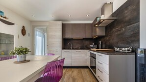 Une cuisine moderne avec un plan de travail blanc, des appareils en acier inoxydable et un plancher en bois.