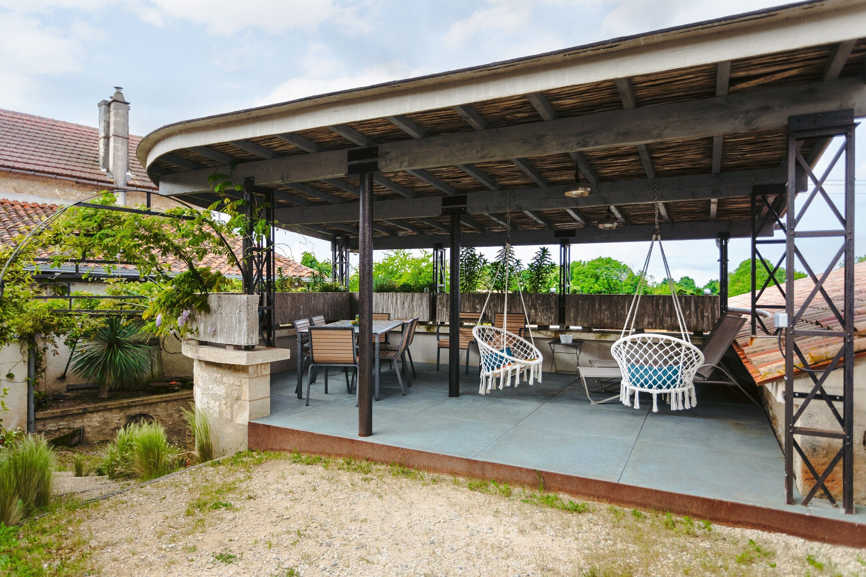 An outdoor patio with a covered seating area, including chairs and tables.