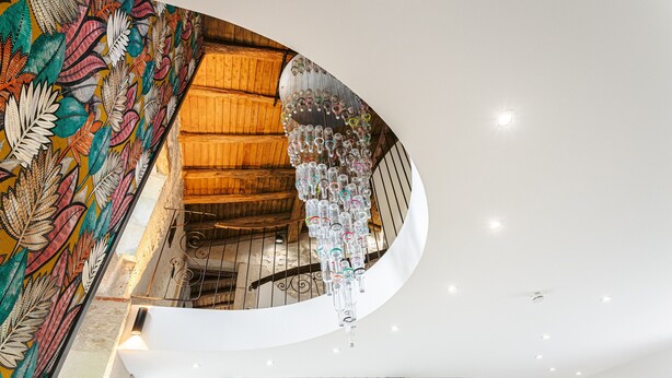 Una escalera de caracol con interior de madera y un mural colorido en la pared.