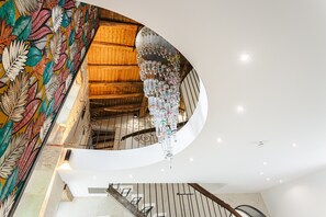 Un escalier en colimaçon avec une structure intérieure en bois et une fresque colorée sur le mur.
