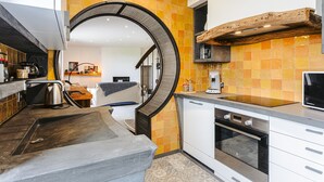 Una cocina moderna con un arco curvo, horno empotrado y una viga de madera sobre la encimera.