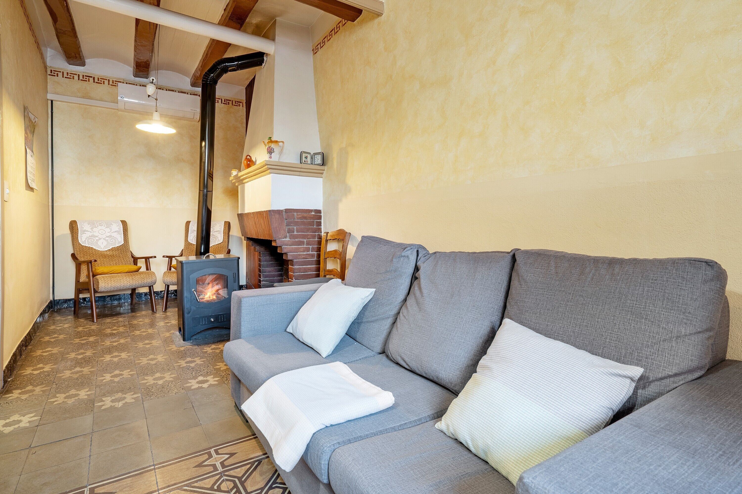 Una sala de estar con sofá, sillas, chimenea y piso estampado.