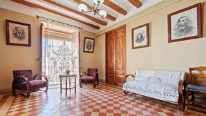 A room with a checkered floor, wooden ceiling beams, a sofa, two armchairs, a table, and framed portraits on the walls. - Holiday Home 'Ca Cedó' with Shared Terrace, Wi-Fi and Air Conditioning (La Serra d'Almos)