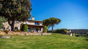 A stone house with a large tree, a grassy lawn, and a clear blue sky. - Apartment 'Casa Rose' with Sea View, Wi-Fi and Air Conditioning (Orbetello)