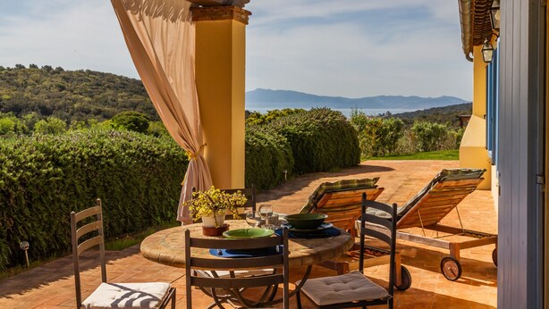 Un patio con una mesa dispuesta para dos, una silla y una tumbona.