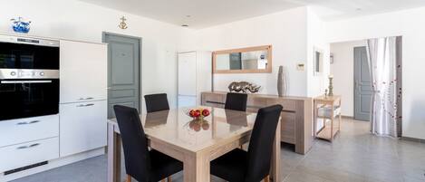 A modern kitchen with a dining area, white cabinetry, and a large mirror.