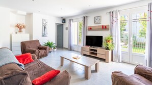 A modern living room with a sofa, coffee table, TV, and large windows. - Holiday Home “Villa De Maithe” with Private Terrace, Wi-Fi and Air Conditioning (Sernhac)