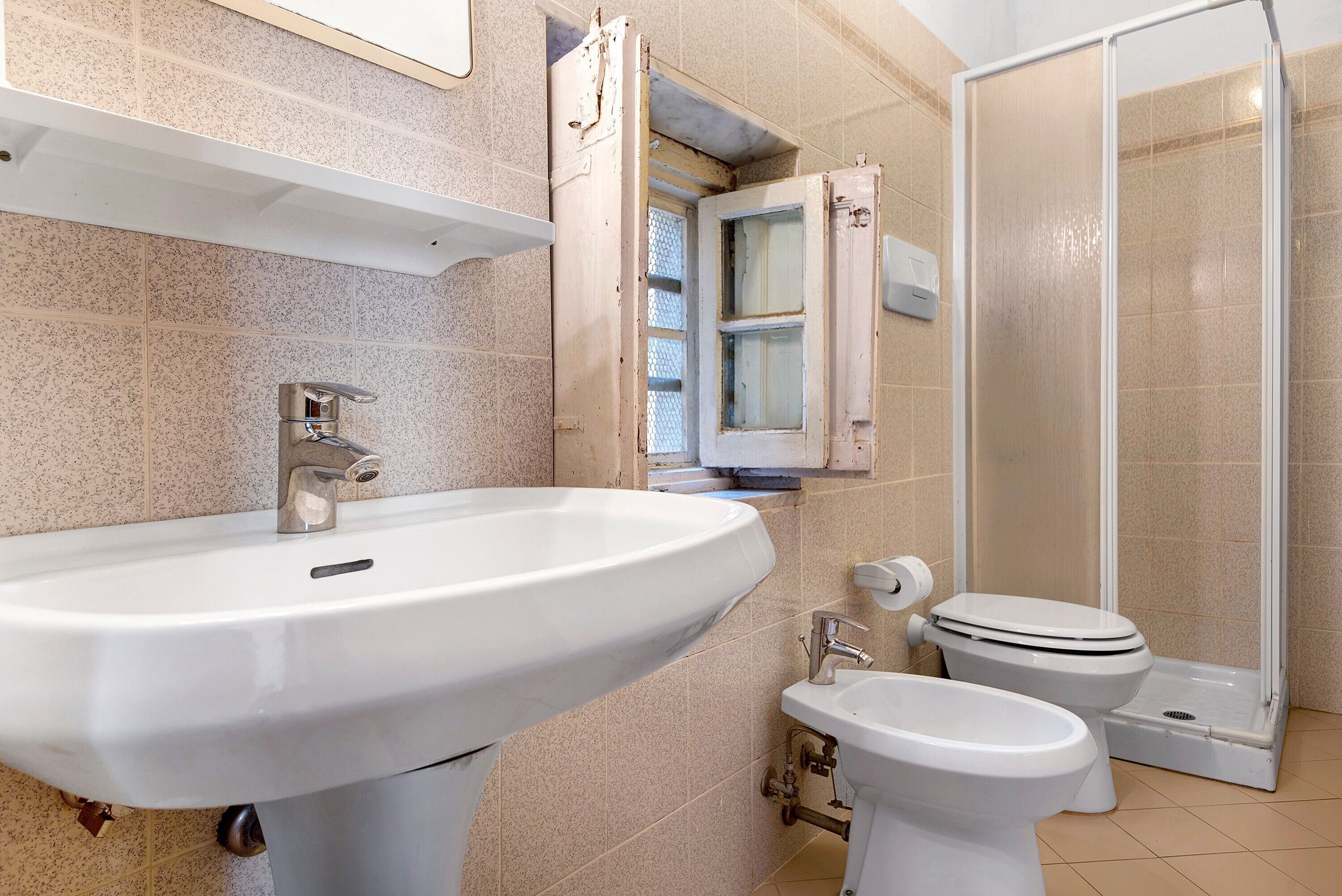 A bathroom with a sink, toilet, bidet, and shower.