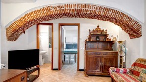Ein Wohnzimmer mit Fernseher, Holzmöbeln, einer Couch und einem Ziegelbogen.