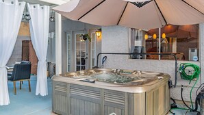 Een jacuzzi met een beige deksel, een tafel met stoelen, en een hanglamp.