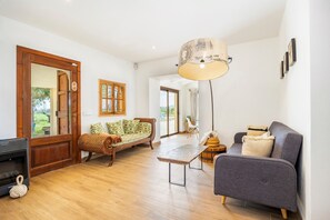 Un salon spacieux avec un plancher en bois, un canapé, un banc et une lampe.