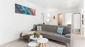 En moderne stue med en grå sofa, et rundt sofabord og et billede på væggen.