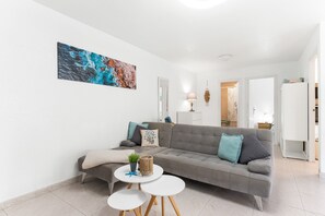 A modern living room with a grey sofa, a round coffee table, and a painting on the wall. - Apartment 'Casa Reina Abajo' with Shared Pool, Wi-Fi and Air Conditioning (Orihuela)