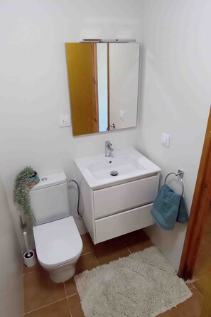 A bathroom with a toilet, sink, mirror, and a towel rack. - Costa Arenal Apartment with Sea View, Premium Pool and Close to the Beach (Arenal d'en Castell)