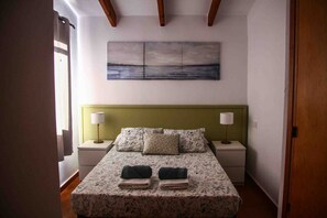 A bedroom with a bed, two nightstands, a green headboard, and a painting above the bed. - Costa Arenal Apartment with Sea View, Premium Pool and Close to the Beach (Arenal d'en Castell)