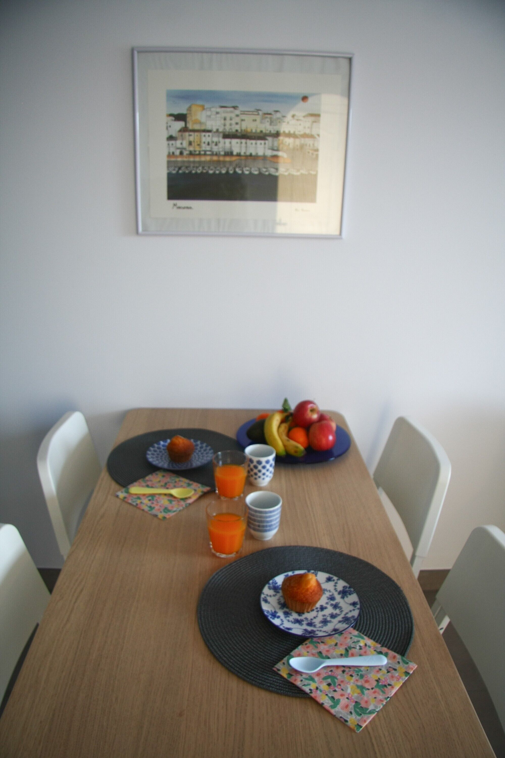 A dining table with plates, a bowl of fruit, and a framed picture on the wall.
