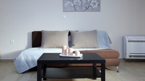A modern living room with a sofa, a coffee table with candles, and an air conditioner. - Apartment 'Neapolis' with Private Terrace, Wi-Fi and Air Conditioning (?e???da)