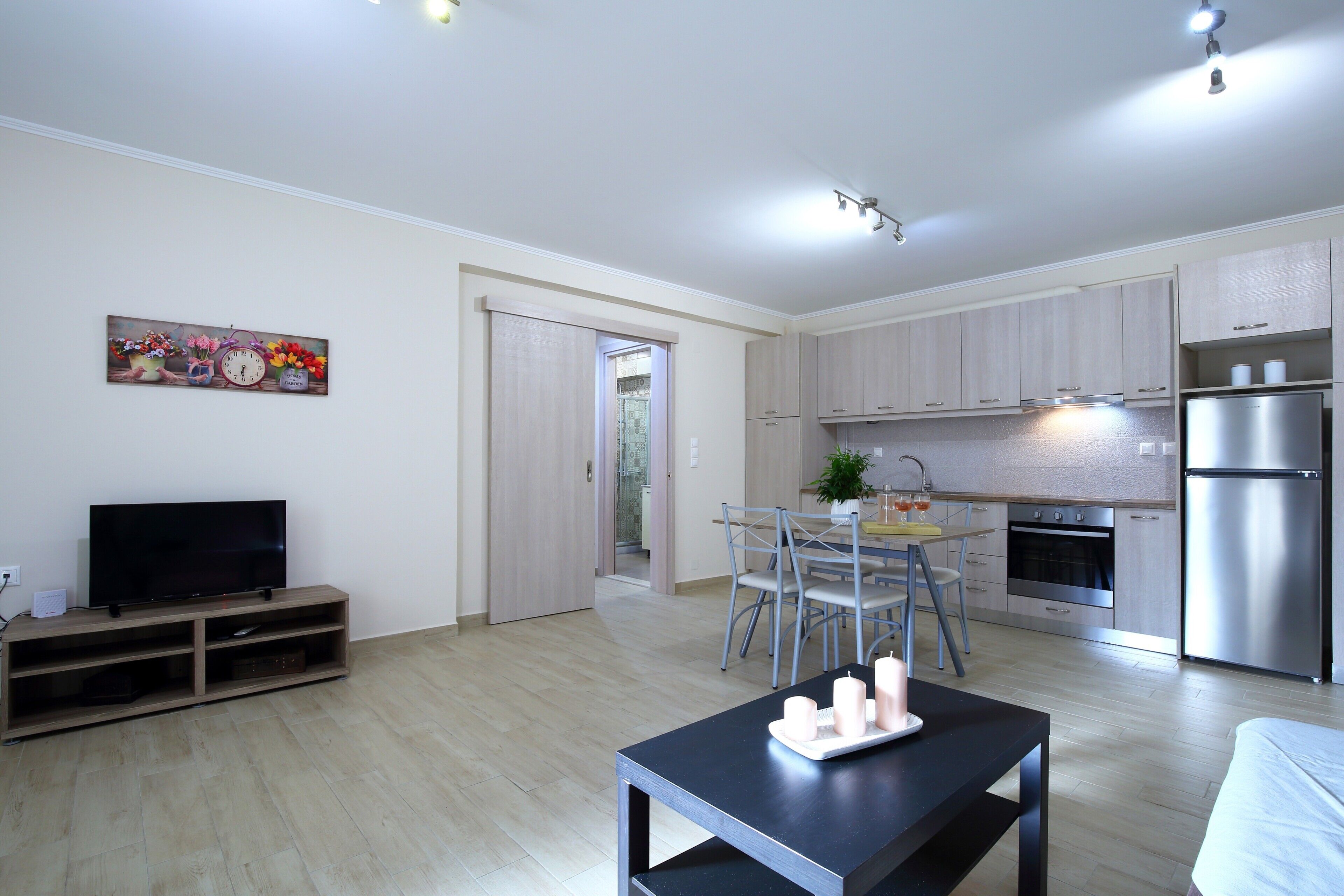 Eine moderne Küche mit Edelstahlgeräten, einem Essbereich mit Tisch und Stühlen sowie einem Flachbildfernseher auf einem Holzboden.