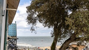 En terrasse med udendørs siddepladser med udsigt over en strand og havet.