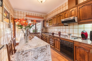 A kitchen with wooden cabinets, a stove, and a dining table with a lace tablecloth. - Holiday Home 'Casa Venta Ruizo' with Mountain Views, Wi-Fi and Air Conditioning (Lorca Murcia)