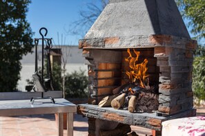 Ein Grill aus Stein mit Schornstein, Brennholz und Grillwerkzeug.