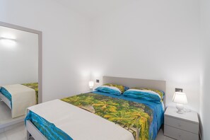 Une chambre à coucher comprenant un lit, des tables de chevet, une commode, une lampe et un miroir.