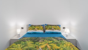 A bed with a tropical-themed bedspread, two bedside lamps, and a nightstand.