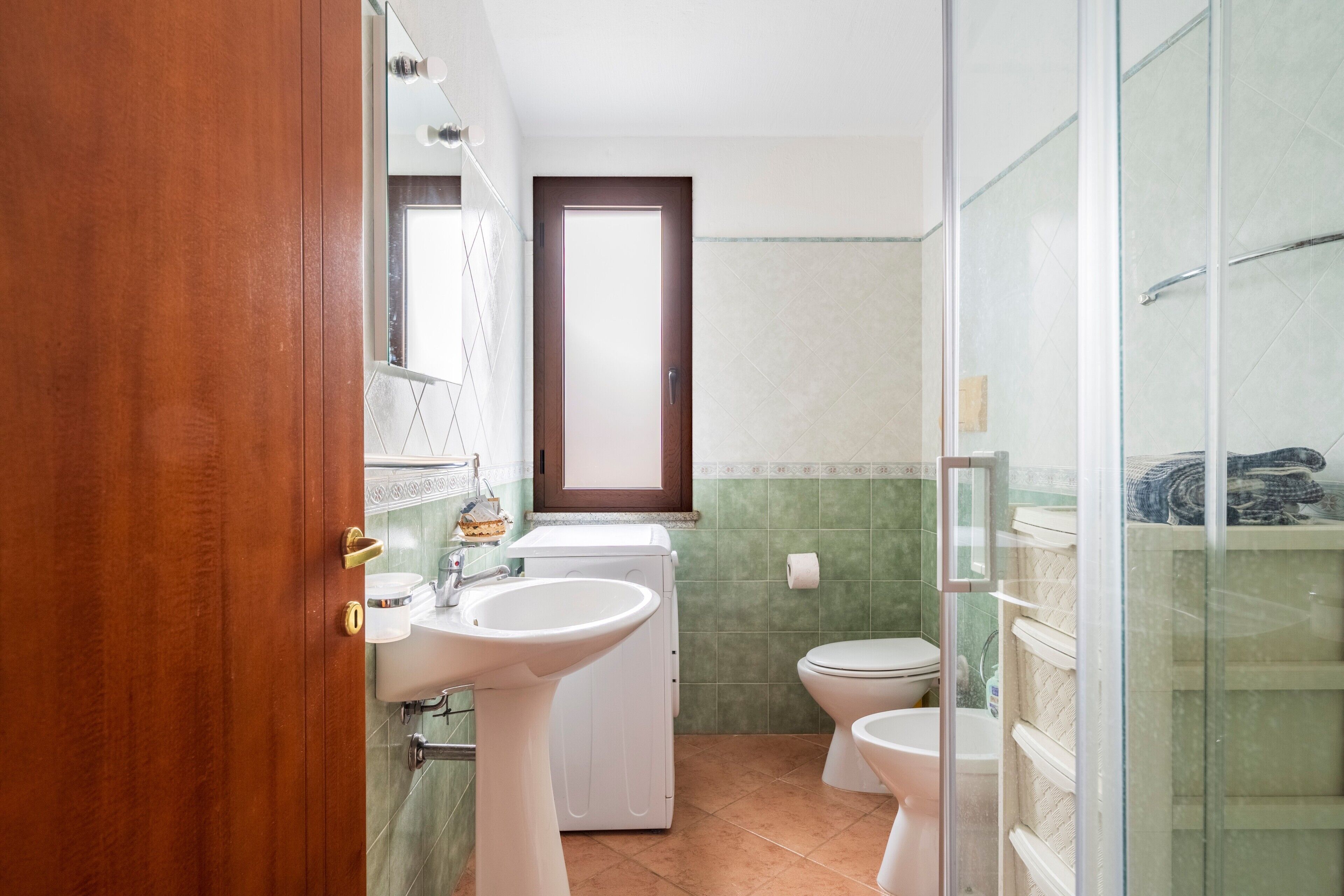 Uma casa de banho com lavatório, sanita e máquina de lavar roupa.
