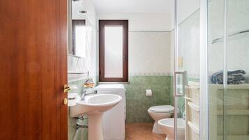 Uma casa de banho com lavatório, sanita e máquina de lavar roupa.